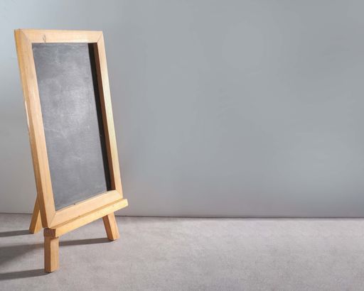 A closeup of a blank blackboard with a wooden frame against a gray background