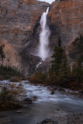 A vertical shot of a waterfall flowing down between cliffs