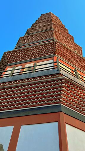 A low-angle shot of an ancient pagoda against a blue sky in vertical