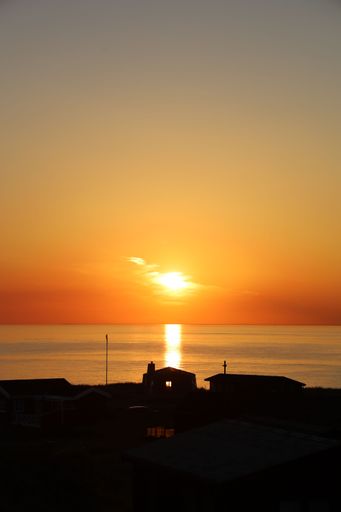 A vertical shot of a beautiful sunset on the shore in Lonstrup, in Vendsyssel, Denmark