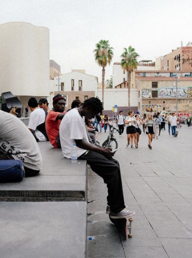 A vertical shot of black young skaters sitting and listening to music in the park