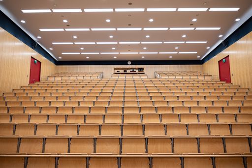 An empty lecture hall of University of Freiburg with wooden chairs