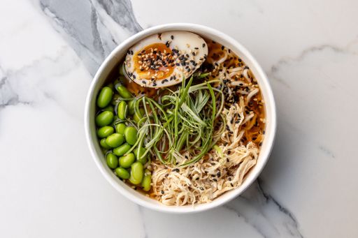 A top view of a delicious ramen bowl with beans and an egg served on the marble table