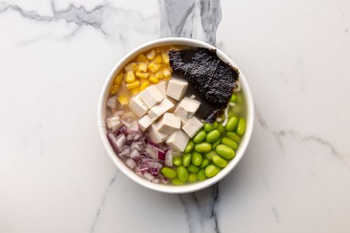 A top view of a delicious poke bowl with beans and corn served on the marble table