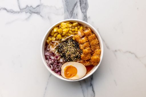 A top view of a delicious ramen bowl with meat and an egg served on the marble table