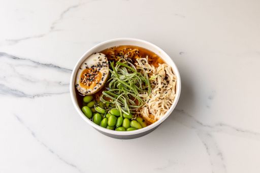 A top view of a tasty noodle soup with green beans and an egg on the marble table