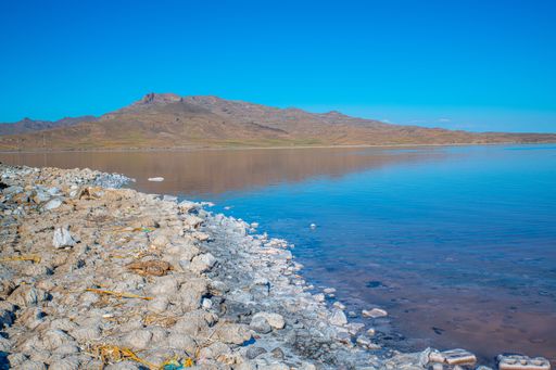 A scenic view of rocky shore of Lake Urmia in Iran under a cloudless blue sky on a sunny day