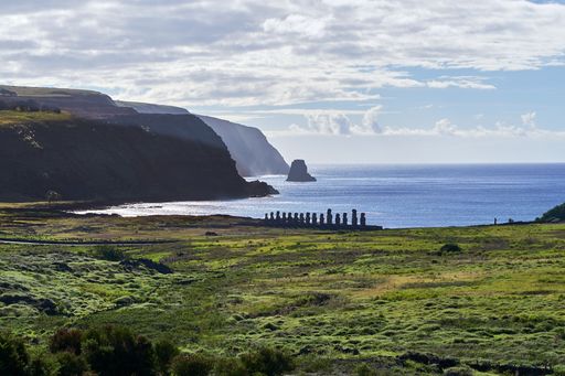 The Moai stone monolithic statues in a row surrounded by grass and water, Easter Island, Chile