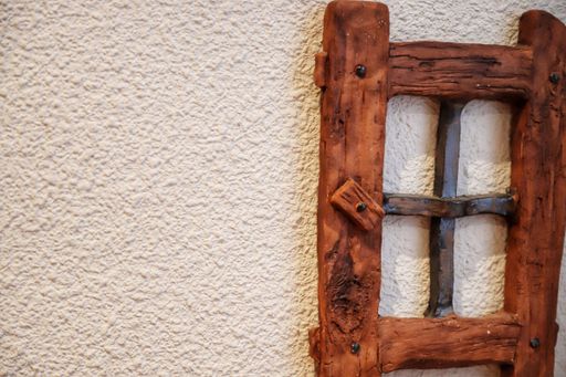 A shape of a brown antique window hung on a white wall.