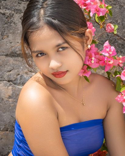 Portrait of beautiful Filipino girl posing in front of camera near pink flowers on Capinticillo Island, Bogo City, Cebu, Philippines
