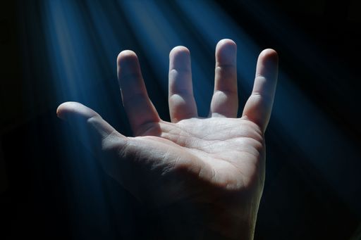 A man's palm gesturing up in the shadows. Hope and faith concept.