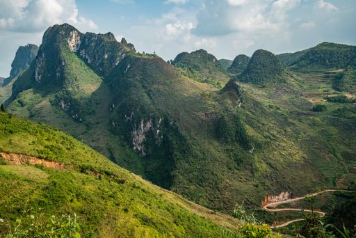 An aerial shot of high green mountains under the cloudy sky in Vietnam