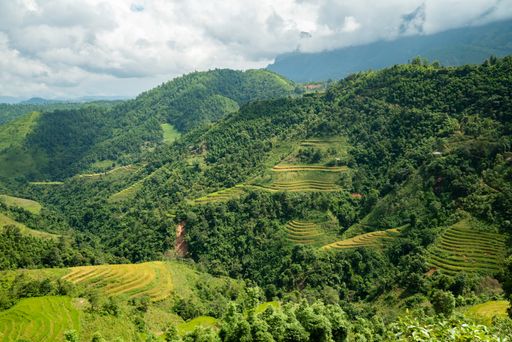 A high angle shot of a beautiful green landscape with high mountains under the cloudy sky in Vietnam