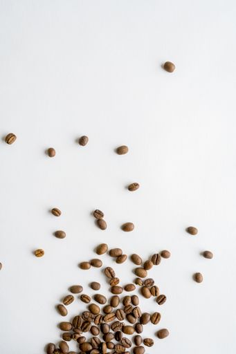 An overhead shot of coffee beans scattered on a white surface