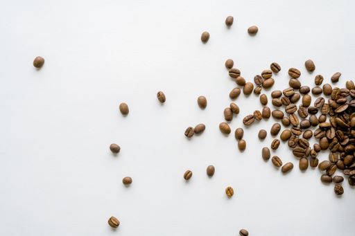 An overhead shot of scattered coffee beans on a white surface - great for background