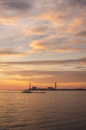A mesmerizing orange sunset with fluffy clouds over the calm sea water