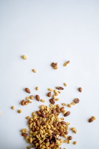 A vertical shot of different types of nuts on a white surface - great for background