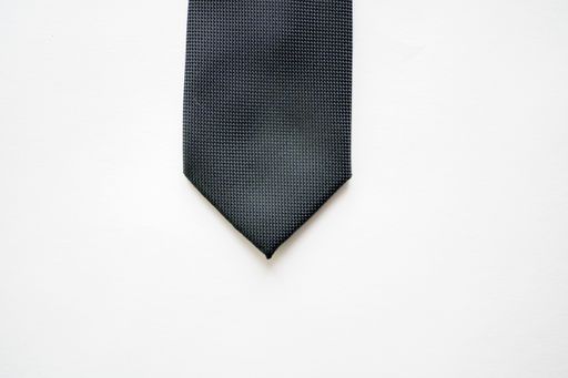 An overhead shot of a black tie on a white surface