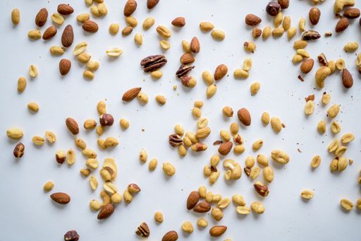 An overhead shot of scattered different types of nuts on a white surface