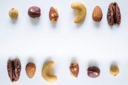 An overhead shot of different types of nuts on a white surface - great for writing a text
