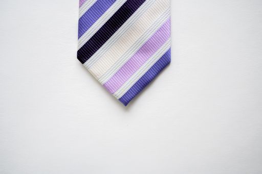 An overhead shot of a colorful striped tie on a white surface
