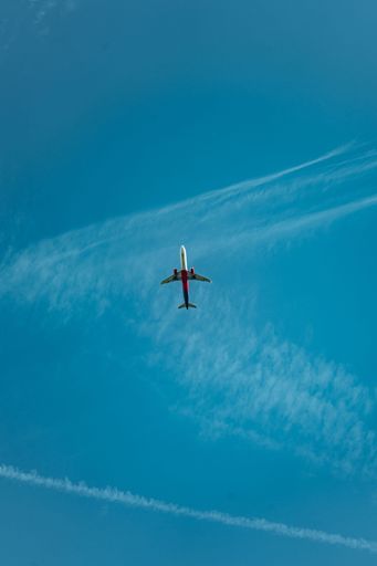 A vertical low angle shot of an airplane flying in the sky on a sunny day