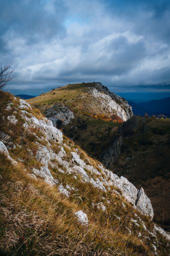 A vertical shot of the rocky peaks of the mountain with the gloomy cloudy sky in the background