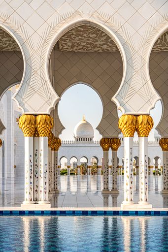 Marble and gold domes at the reflective pool at Sheikh Zayed Grand Mosque in Abu Dhabi, United Arab Emirates.