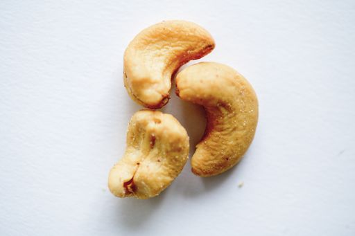 an overhead closeup shot of cashews on a white surface