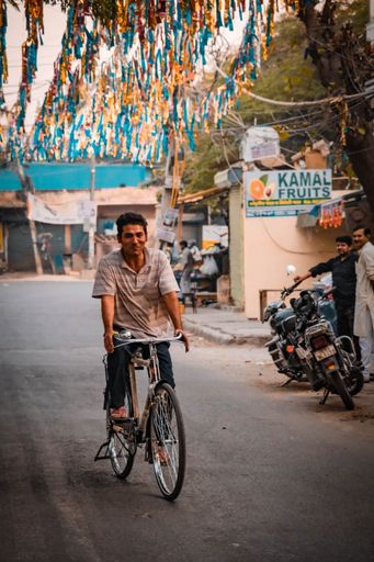 A cyclist riding down the road in Dilshad Garden, Delhi, India, vertical