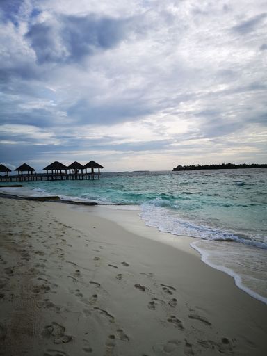 A vertical of open stilt houses on the waters of a sea under a cloudy sky