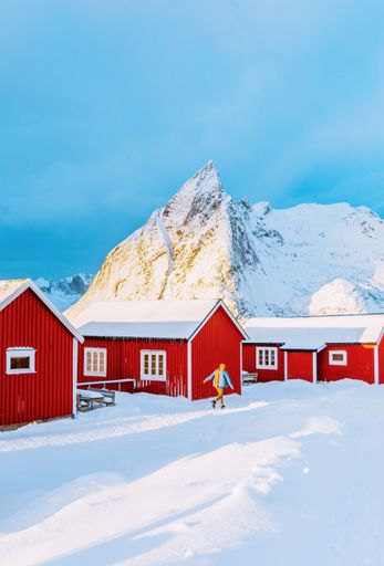 A vertical shot of the small houses in the mountains on a snowy day