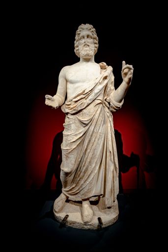 A vertical shot of the statue of Asclepius against black background