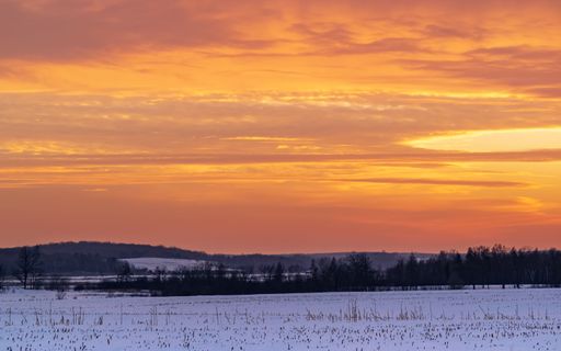 A landscape view of a snow-covered field with a warming sunset sky in background, Minnesota
