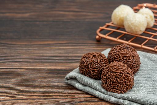 brazilian brigadeiro and beijinho traditional delicious chocolate dessert, party snacks, sweet sprinkle background top view over wooden table