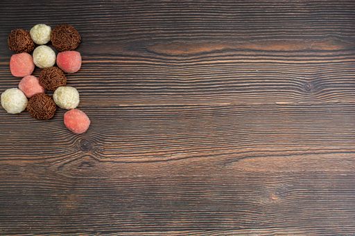 A top view of chocolate Brazilian Brigadeiro, Beiginho and Bicho de Pe on a wooden table with copy space