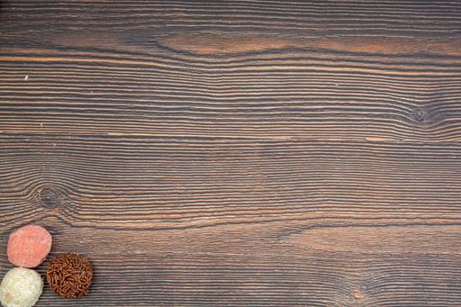 A top view of chocolate Brazilian Brigadeiro, Beiginho and Bicho de Pe on a wooden table with copy space