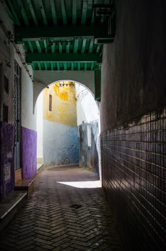 A vertical shot of the sun rays invading a walking tunnel in the middle of the city