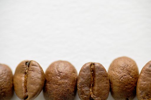 An overhead closeup shot of coffee beans on a white surface
