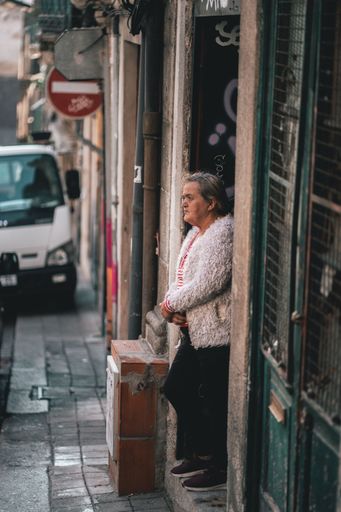 A vertical shot of an old senior lady standing at the street in Porto, Portugal