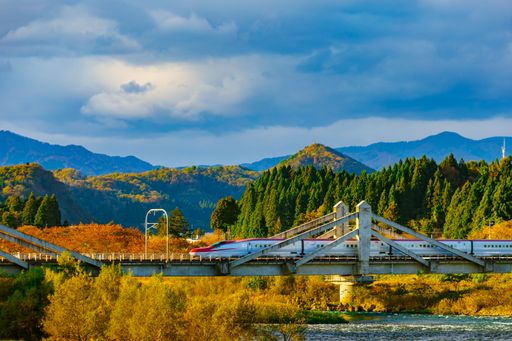 An aerial view of buildings and train Komachi in background of greenery mountains in Daisen