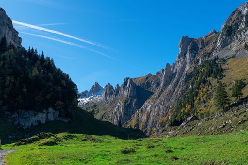 A beautiful view of a house on a hill in a forest with rocks under the blue sky