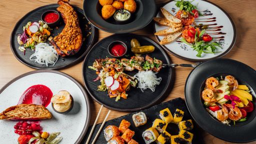 Delicious cheese balls, steak, tartare, sushi rolls, salad with shrimp, and chicken bbq on a table