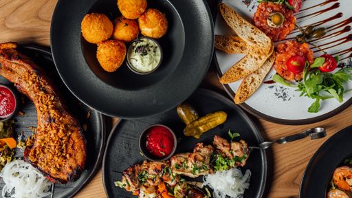 A top view of cheese balls, steak, tartare, and chicken bbq on a table