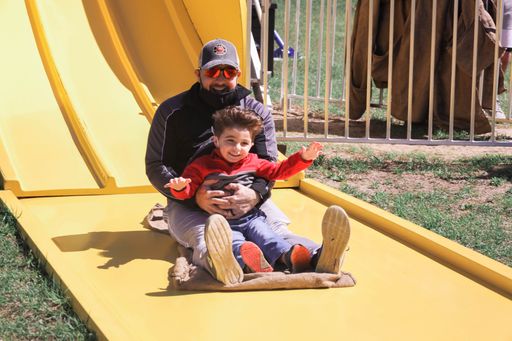 A happy father with his son sliding down the slide in the playground in the Southern hill farms in Clermont