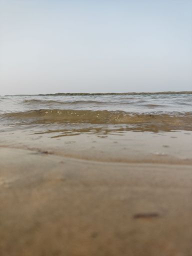 A vertical shot from the beach of the sea waves and the sky