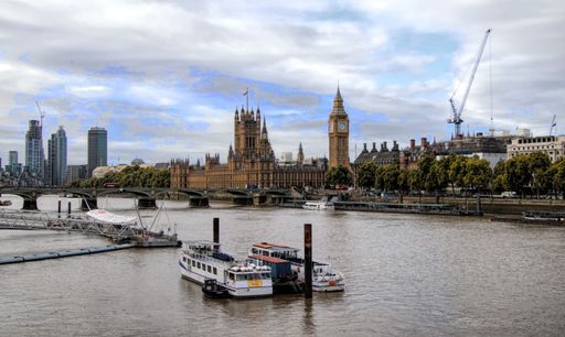 An aerial shot of ships sailing on the river Thames with Big Ben and other buildings on the background