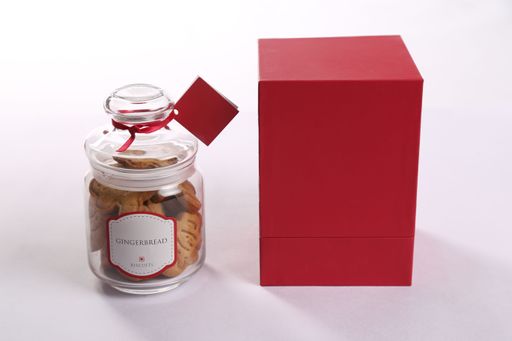 A closeup shot of a jar filled with Christmas Gingerbread biscuits  beside a red box