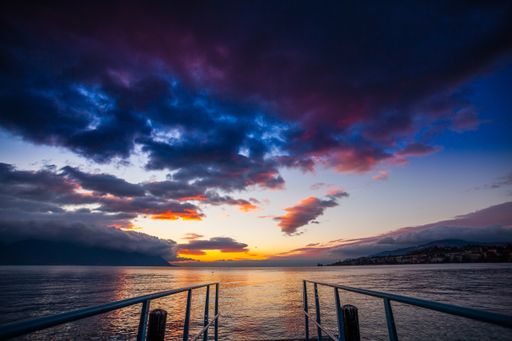 A beautiful shot of a wooden dock near the sea with the reflection of the sunset under the cloudy sky