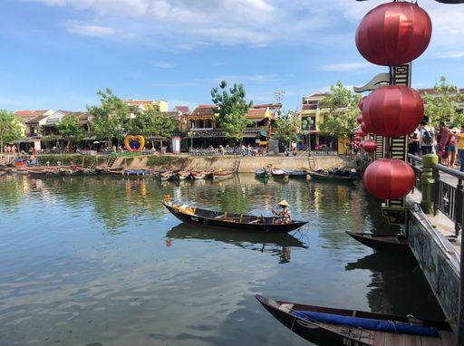 A horizontal image of Vietnamese Nha Ban city, a man sailing a boat in the river in the background of traditional houses